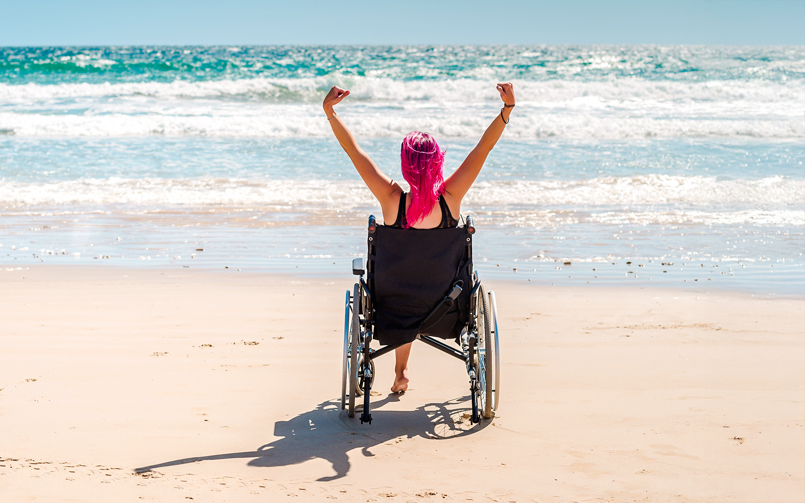 Differently-abled woman in wheelchair enjoying a sunny beach view.