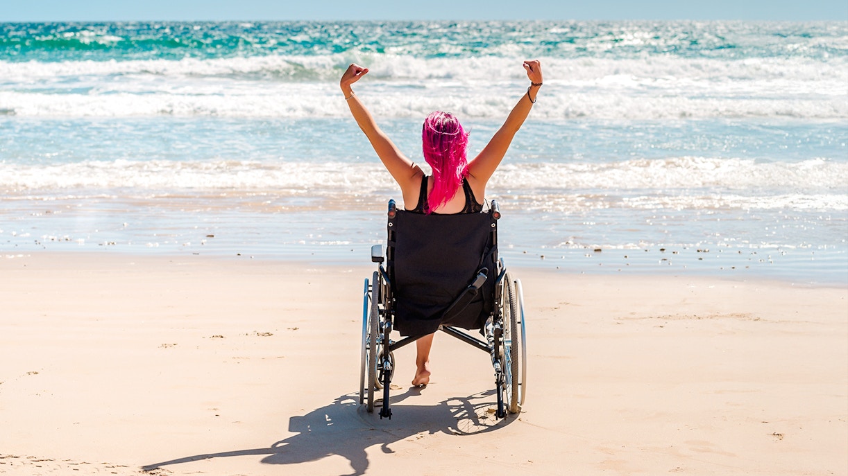 Differently-abled woman in wheelchair enjoying a sunny beach view.