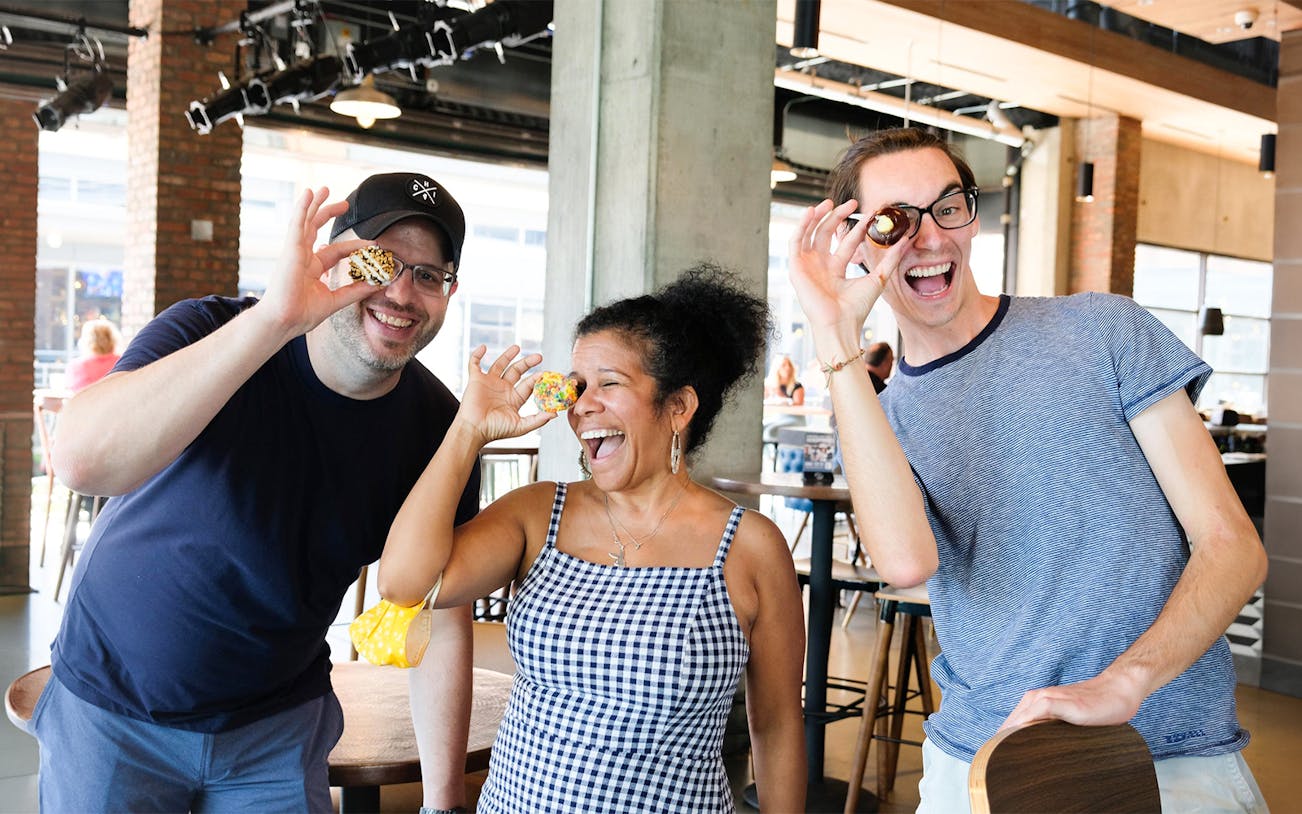 Guests enjoying donuts at a cafe, posing playfully with them.