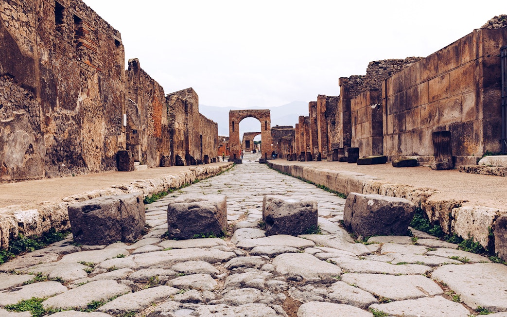 Ancient stone street leading to an archway in Pompeii, Italy.