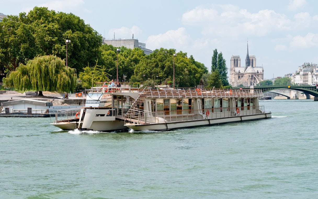 Seine River cruise boat passing Notre-Dame Cathedral in Paris.