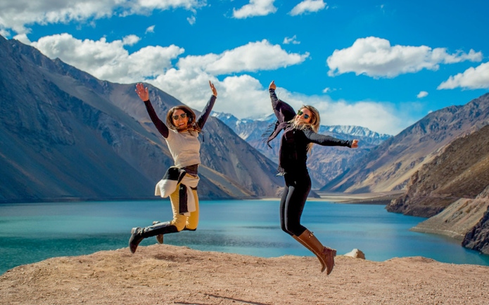 Two people jumping at El Yeso Reservoir in the Andes Mountains, Chile.