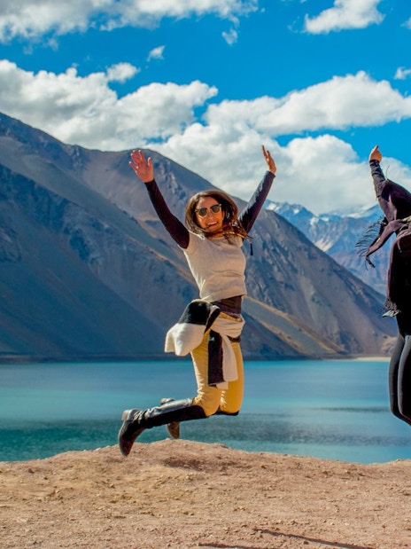 Two people jumping at El Yeso Reservoir in the Andes Mountains, Chile.