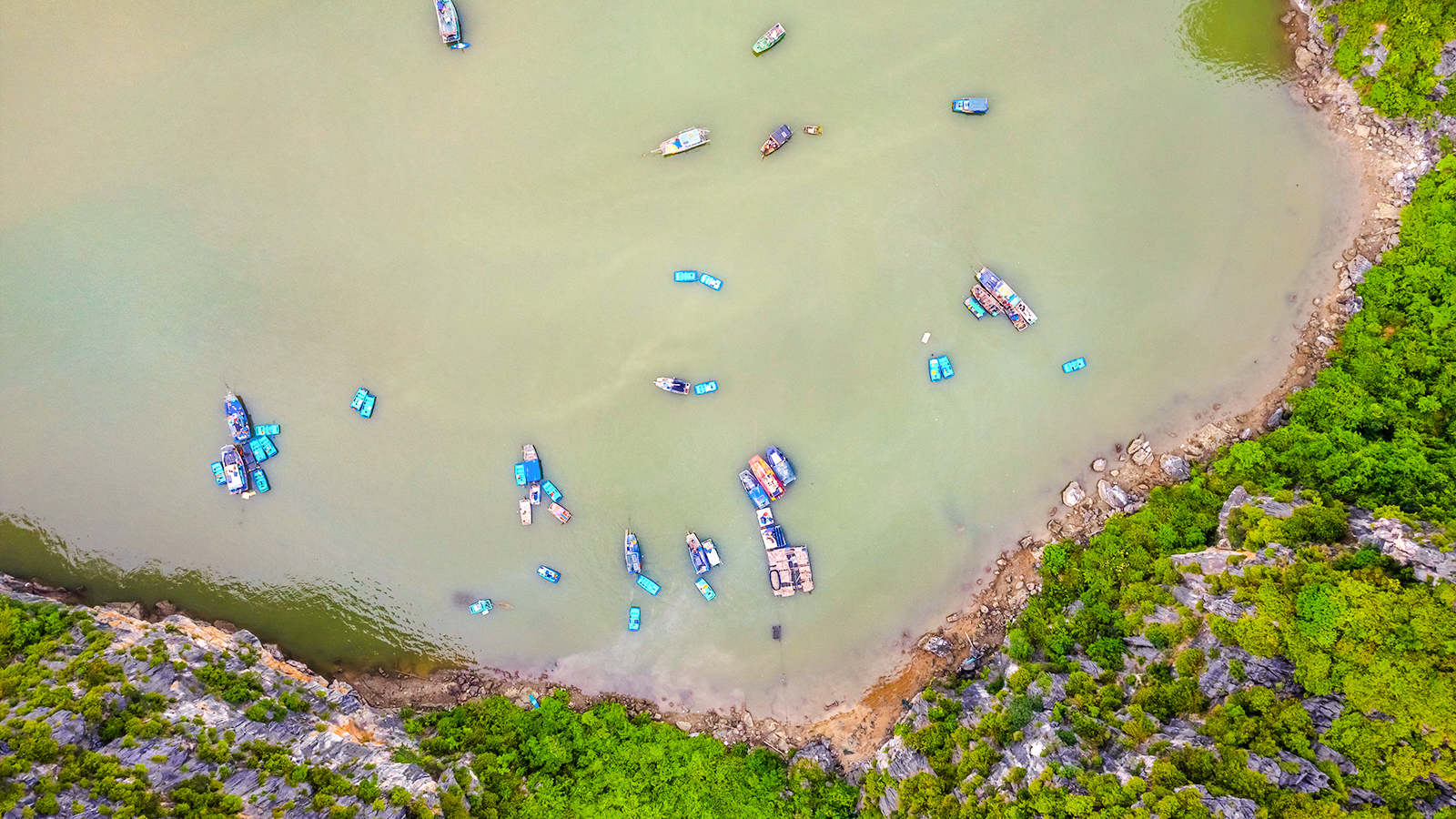 Ba Hang Fishing Village boats on tranquil waters with limestone karsts in Ha Long Bay, Vietnam.