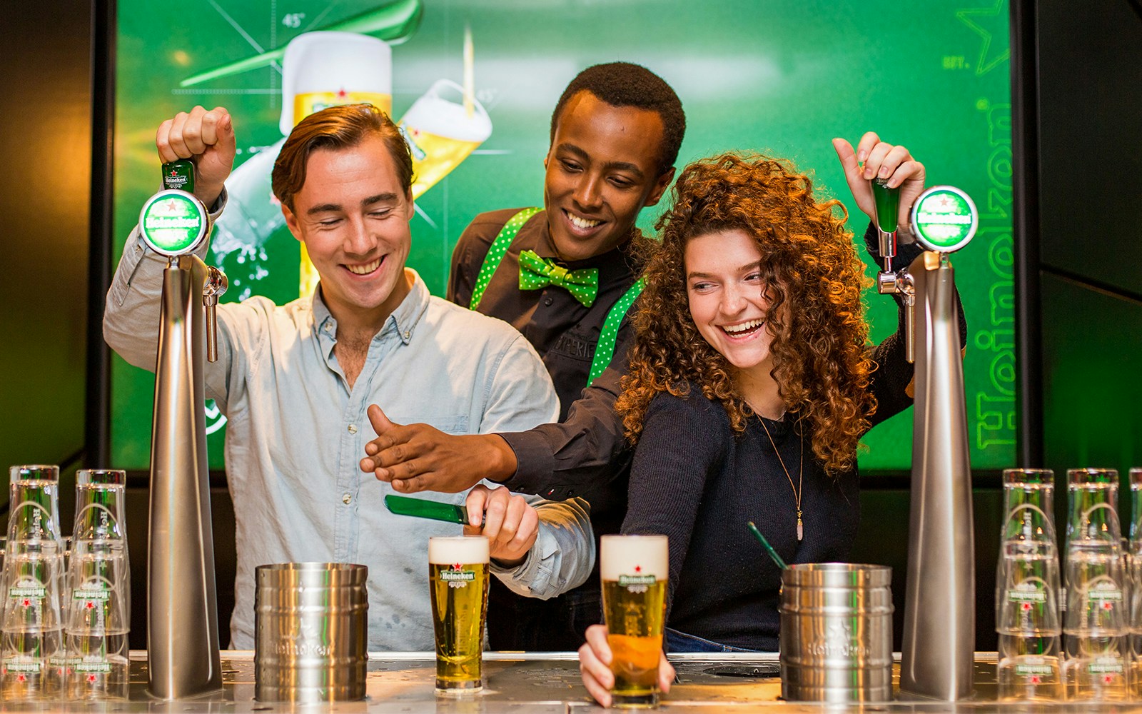 Visitors exploring Heineken brewery in Amsterdam with drinks in hand.
