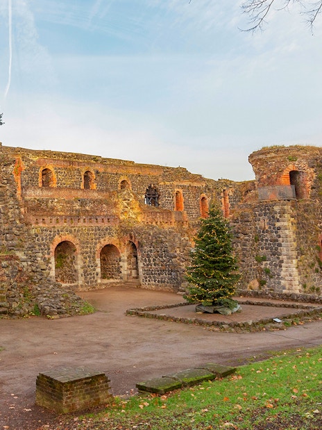 Ancient stone ruins with arches in Duesseldorf, Germany, surrounded by trees.