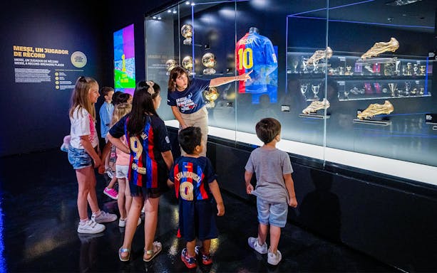 Children viewing Messi's memorabilia at Camp Nou Barca Museum during an immersive tour.