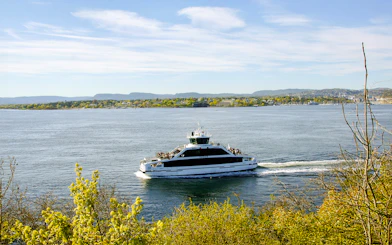 Ferry cruising on Oslofjord with scenic view of coastline and hills in the background.