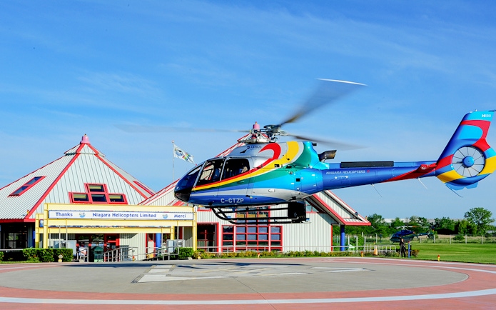 Helicopter taking off from Niagara Falls helipad for aerial tour.