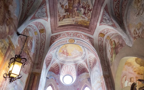 Ceiling frescoes of Bled Castle Chapel with religious scenes and ornate designs.
