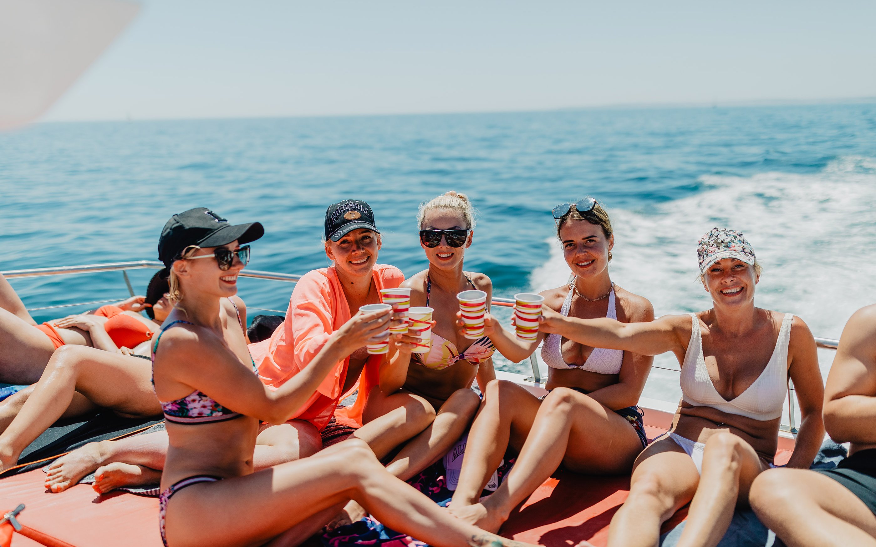Tourists enjoying drinks on a boat during Benagil Caves tour in Algarve, Portugal.