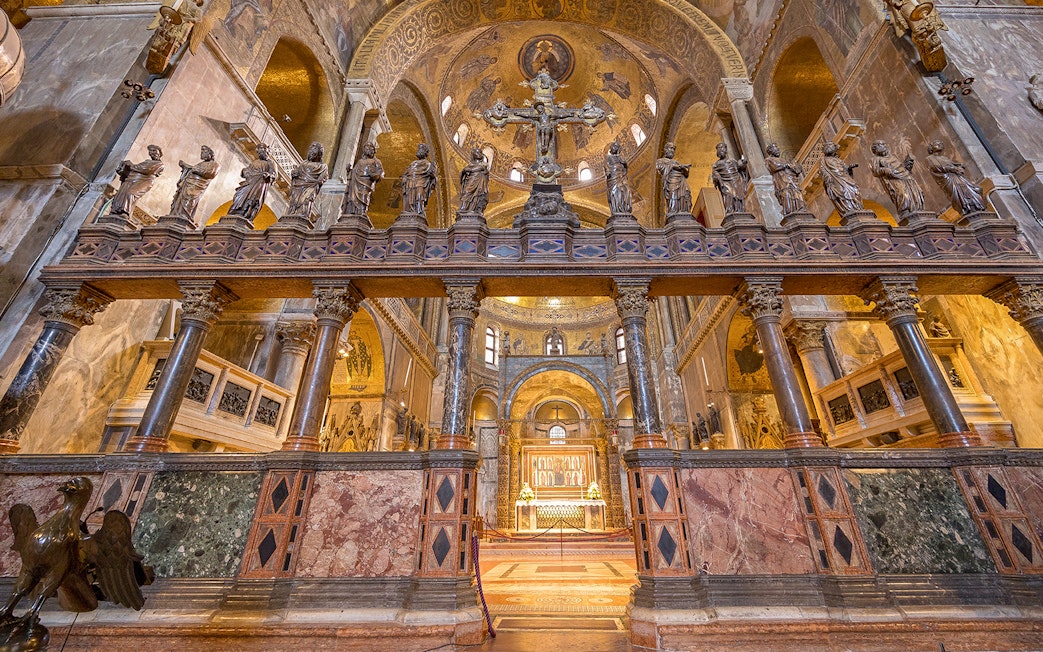 St. Mark's Basilica interior with ornate columns and statues, Venice, Italy.