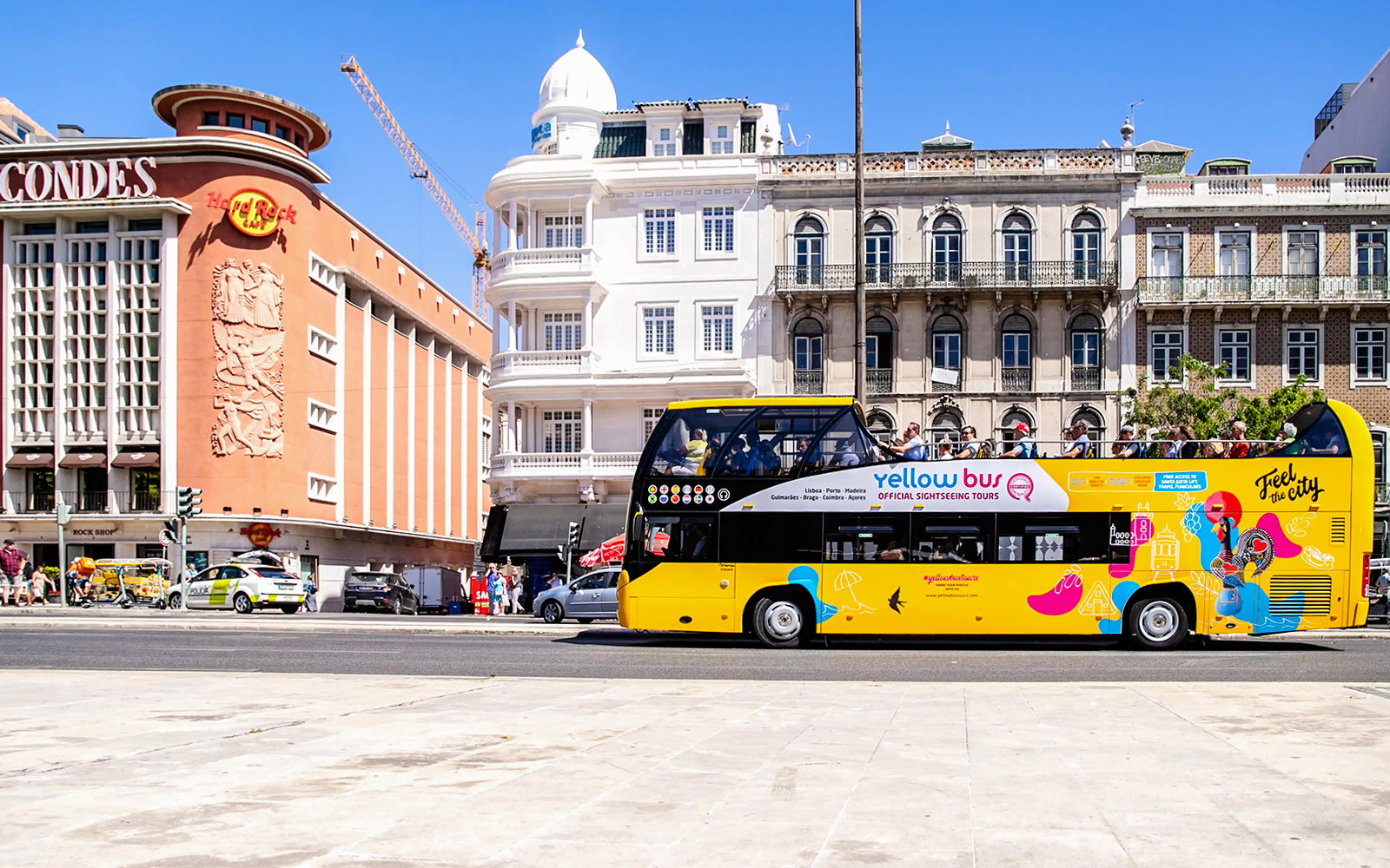 Yellow sightseeing bus in Lisbon passing historic buildings.