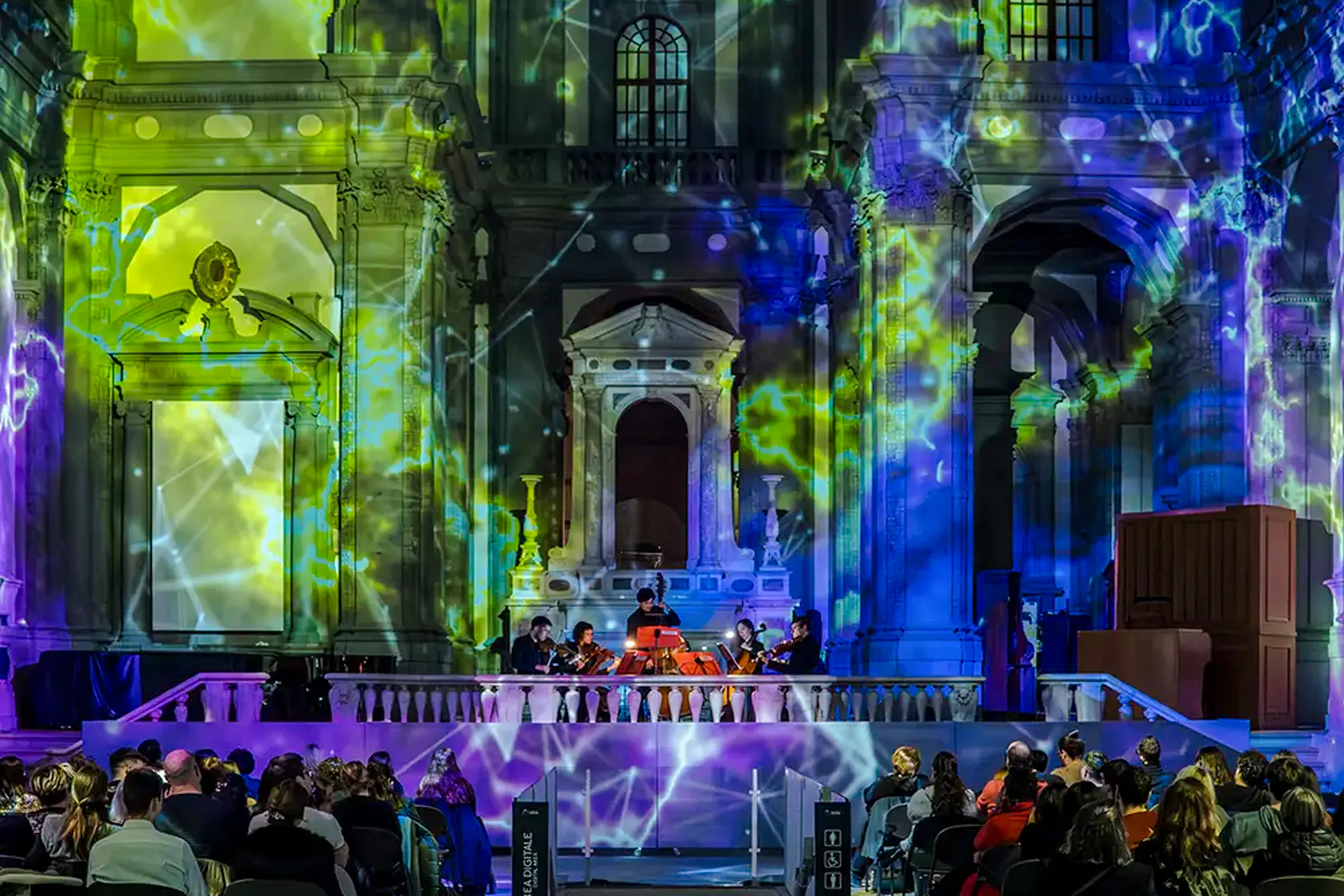 Orchestra performing in a historic Florence venue with colorful light projections.