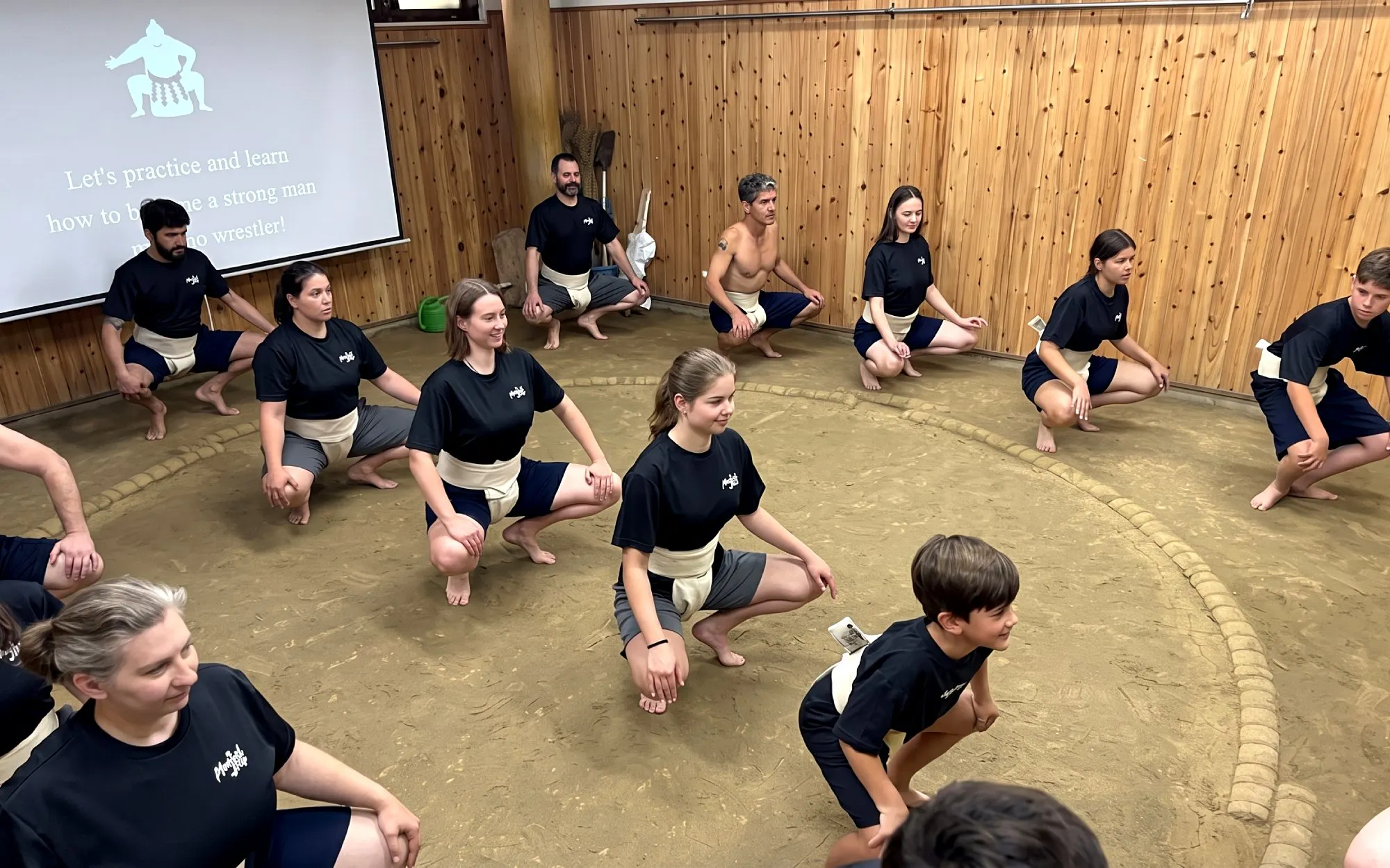 Participants practicing sumo squats in a Tokyo dojo during an authentic sumo experience.