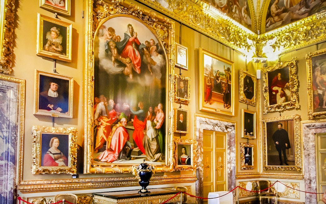 Paintings in the Palatine Gallery, Florence, featuring religious and portrait art in ornate frames.