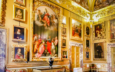 Paintings in the Palatine Gallery, Florence, featuring religious and portrait art in ornate frames.