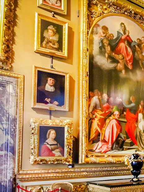 Paintings in the Palatine Gallery, Florence, featuring religious and portrait art in ornate frames.