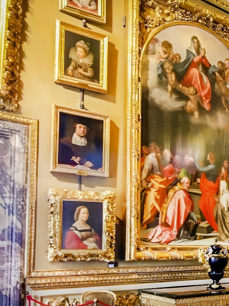 Paintings in the Palatine Gallery, Florence, featuring religious and portrait art in ornate frames.