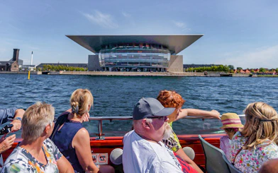 Cruise passengers view Copenhagen Opera House from the water.
