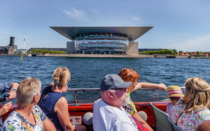 Cruise passengers view Copenhagen Opera House from the water.