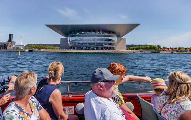 Cruise passengers view Copenhagen Opera House from the water.