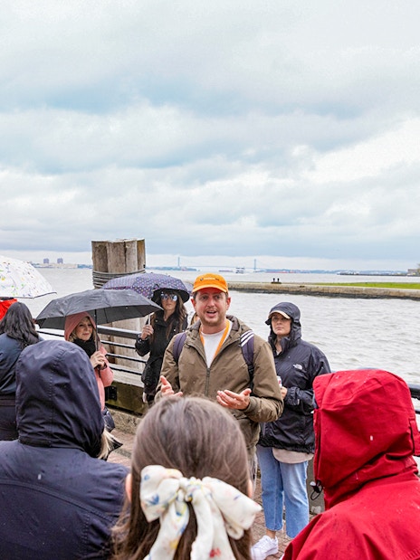 Guide speaking to visitors near Statue of Liberty ferry in New York.