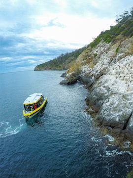 Boat tour near rocky coastline en route to Iron Pot Lighthouse, Tasmania.