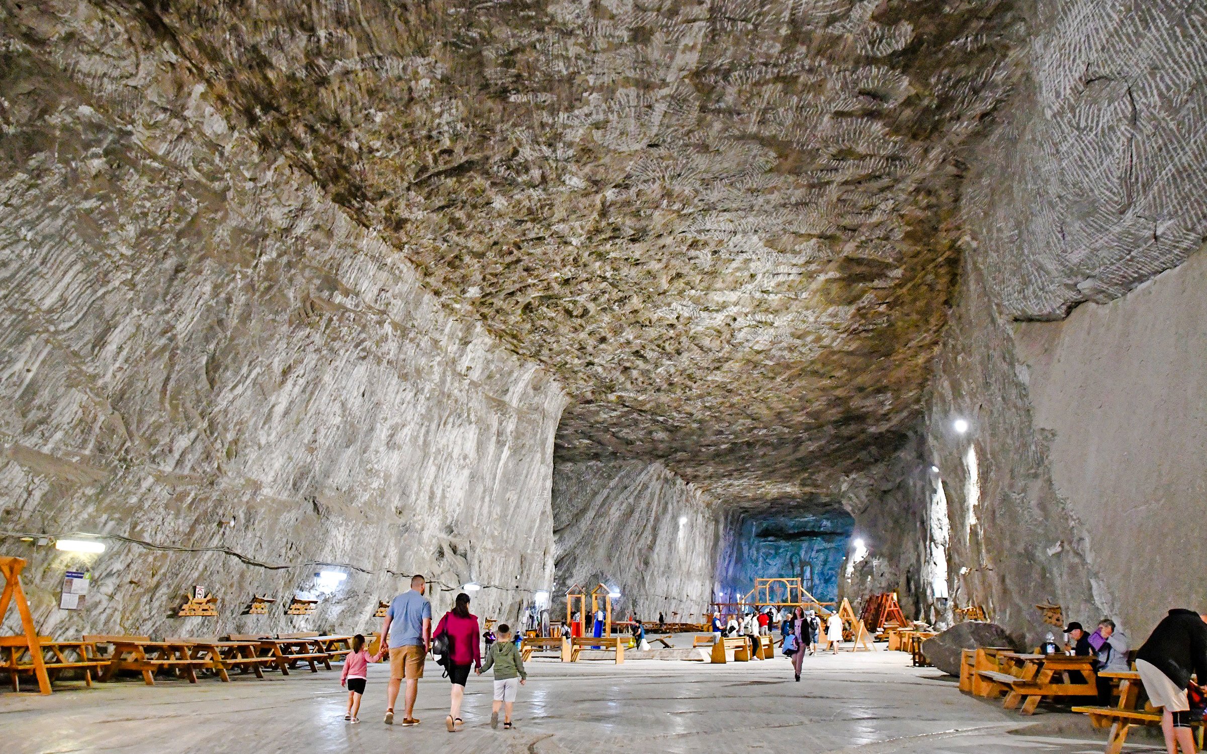 Guests walking inside Slanic Salt Mine, Romania, with large salt walls and benches.