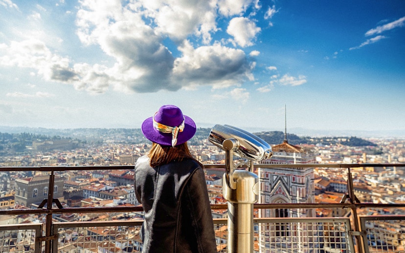 Girl viewing Florence from cathedral dome with cityscape and telescope.