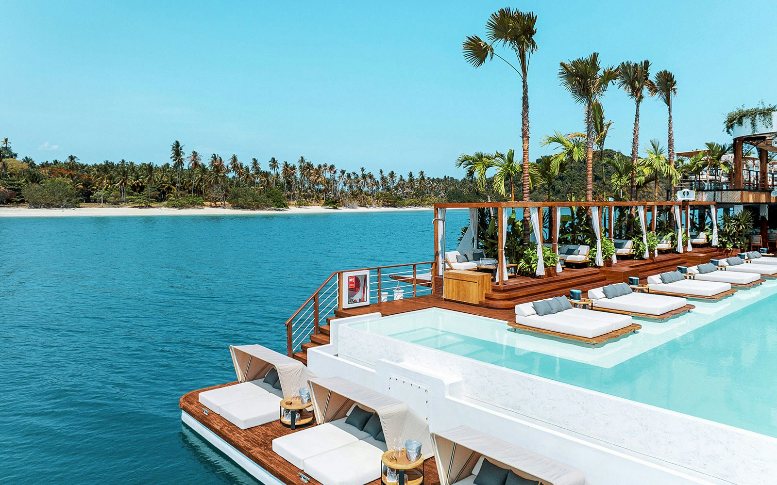 Sitting area with loungers and pool at Yona Beach Club, Phuket, overlooking the ocean.