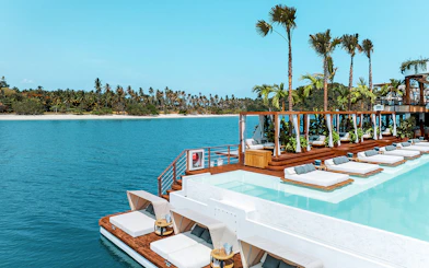Sitting area with loungers and pool at Yona Beach Club, Phuket, overlooking the ocean.