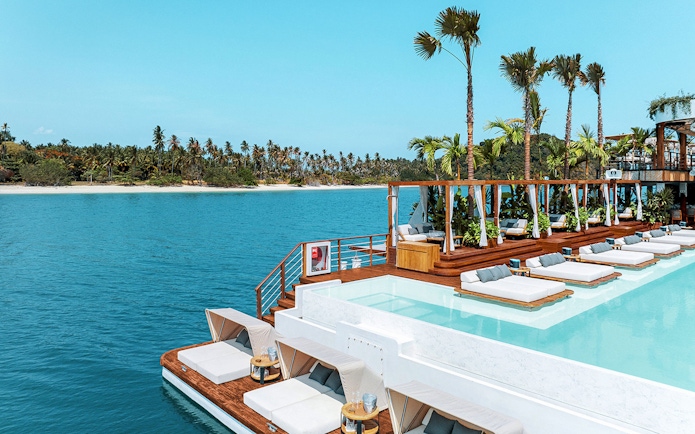 Sitting area with loungers and pool at Yona Beach Club, Phuket, overlooking the ocean.