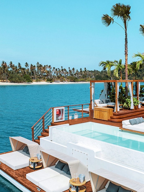 Sitting area with loungers and pool at Yona Beach Club, Phuket, overlooking the ocean.