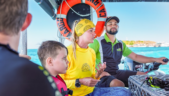 Tour guide explaining snorkeling options on a boat from Cairns to Green Island.