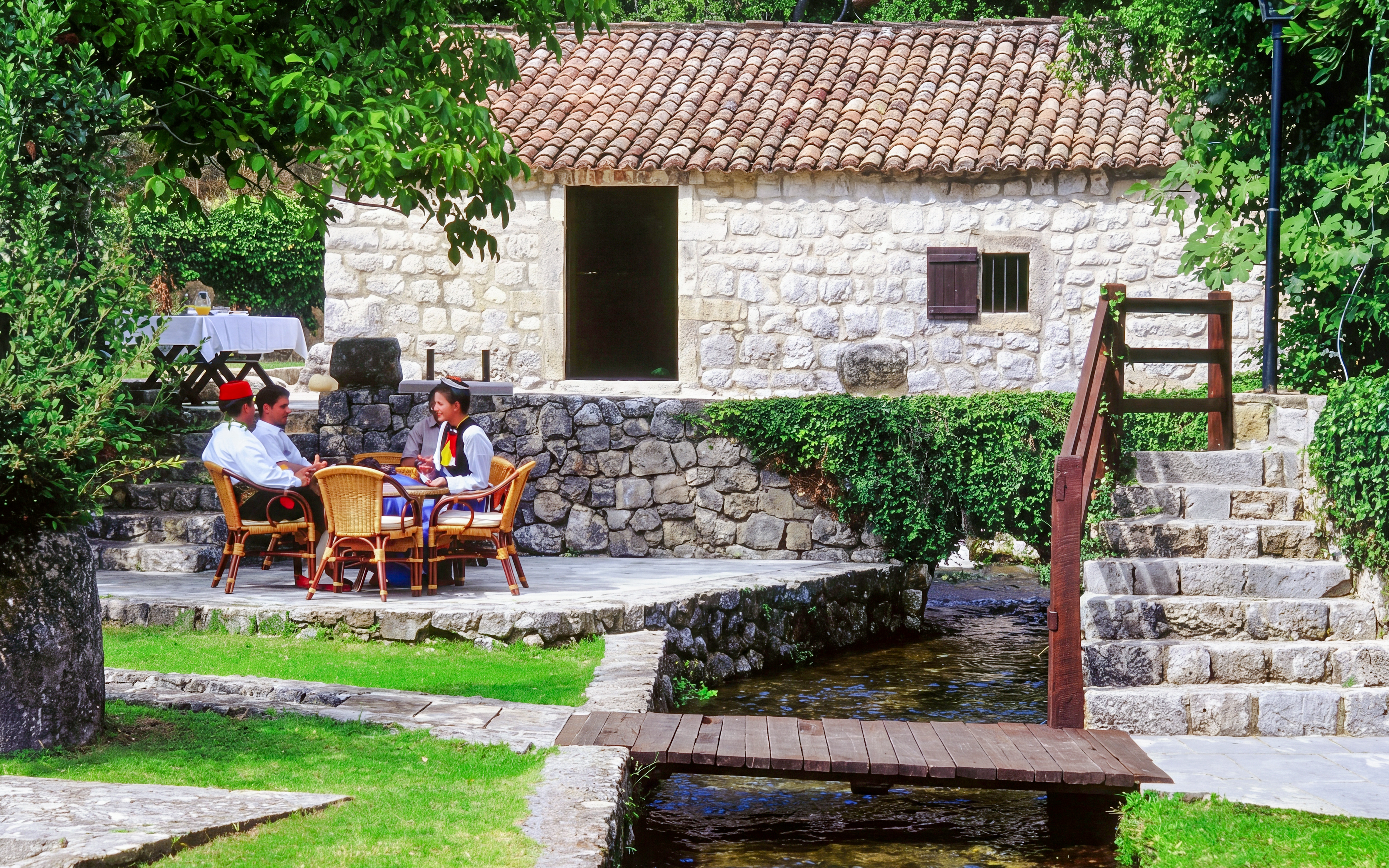 Traditional stone house with people in traditional attire, countryside, Croatia.
