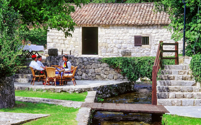 Traditional stone house with people in traditional attire, countryside, Croatia.