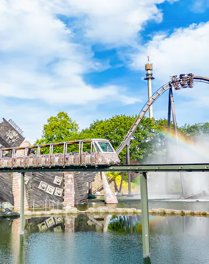 Roller coaster and monorail at Heide Park Resort with water feature and tower in background.