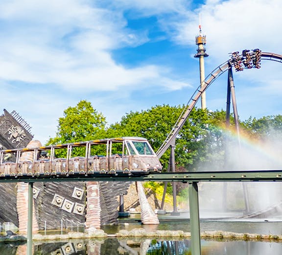 Roller coaster and monorail at Heide Park Resort with water feature and tower in background.