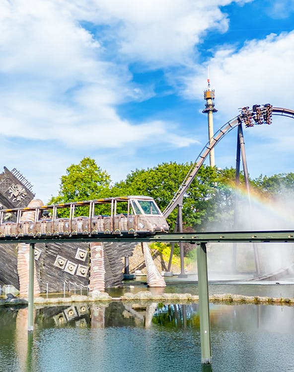 Roller coaster and monorail at Heide Park Resort with water feature and tower in background.