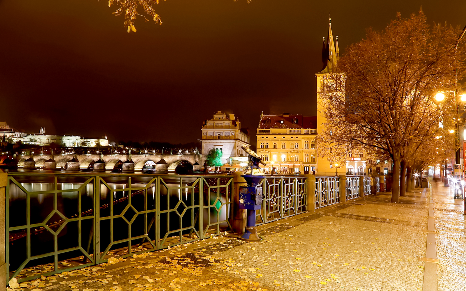 Medieval streets of Prague at night with Charles Bridge in view.