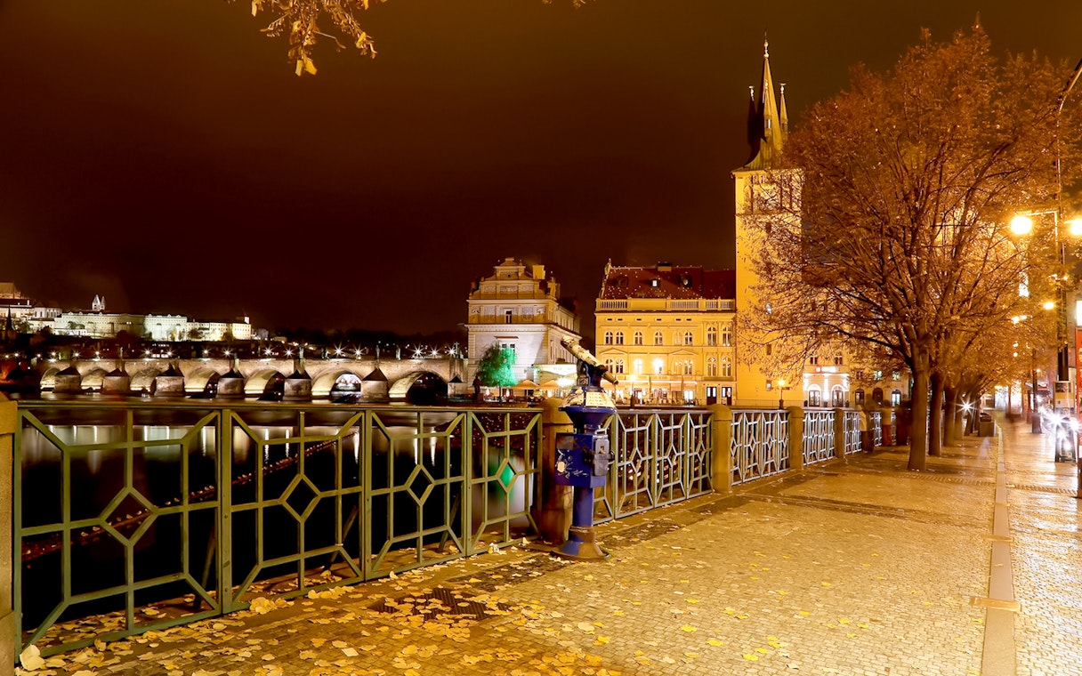 Medieval streets of Prague at night with Charles Bridge in view.