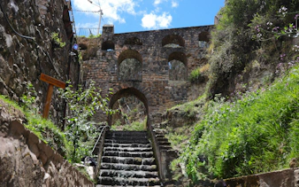 Aqueduct of Sapantiana stone arches and steps surrounded by greenery in Cusco, Peru.