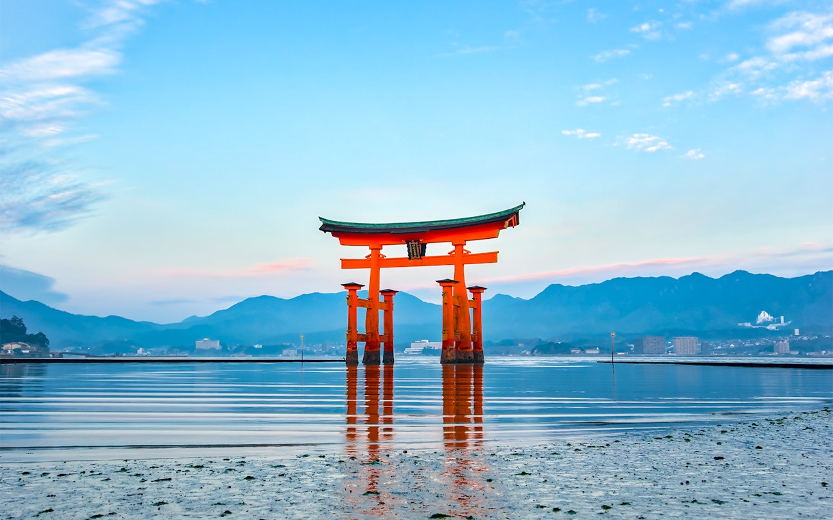 Torii gate at Itsukushima Shrine, Hiroshima, viewed from the water with mountains in the background.