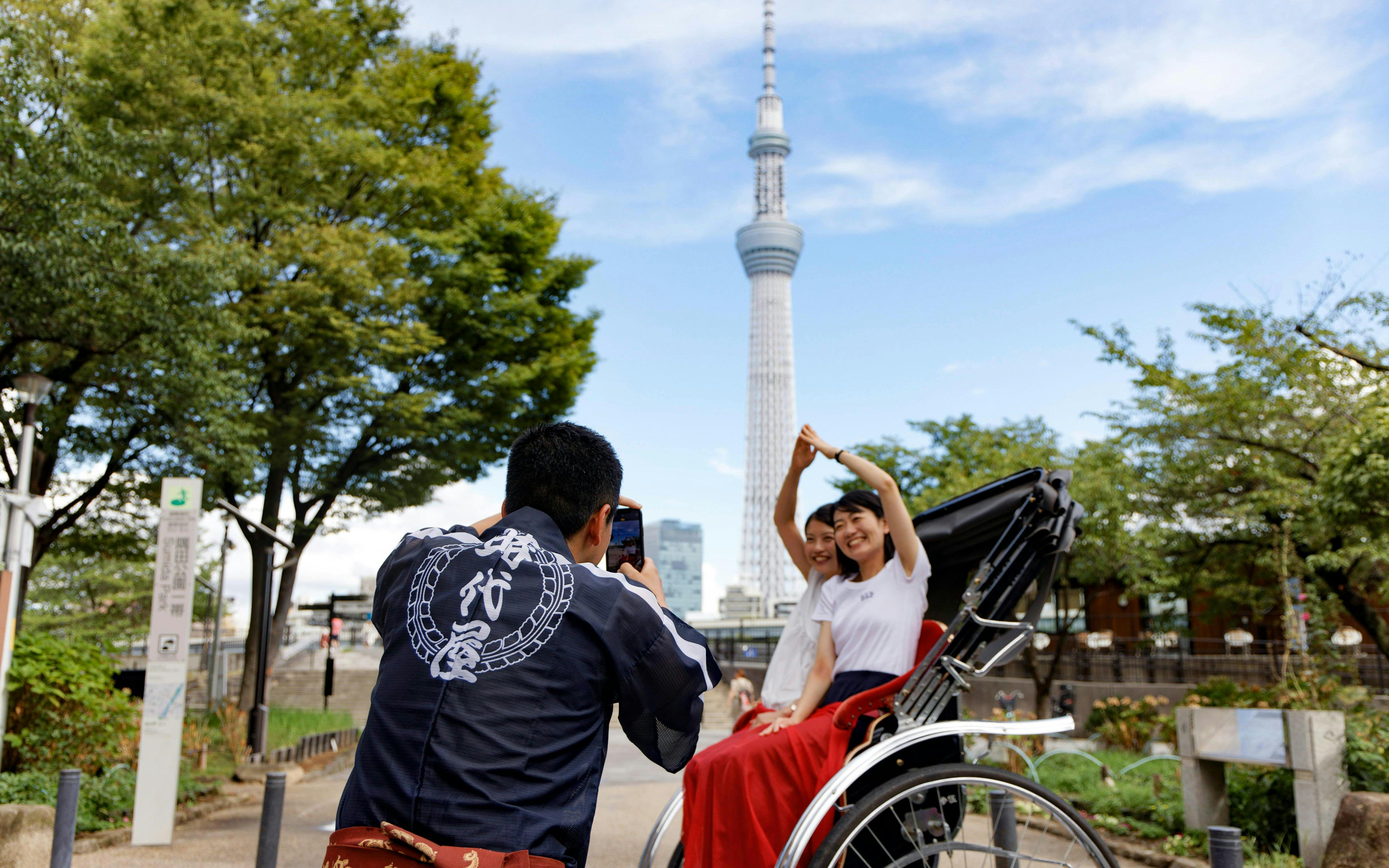 Tourist on rickshaw posing with Tokyo Skytree in background during Asakusa experience.