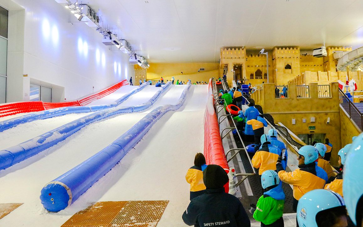 Visitors at Snow Dunes Theme Park preparing for snow tubing on indoor slopes.