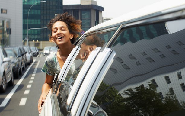 Person enjoying a car ride in Singapore city, reflecting urban buildings.