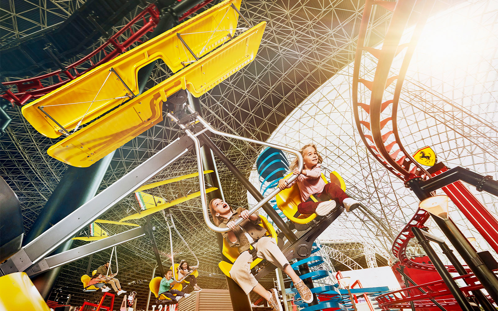 Visitors enjoying a ride at Ferrari World Abu Dhabi under the iconic roof structure.