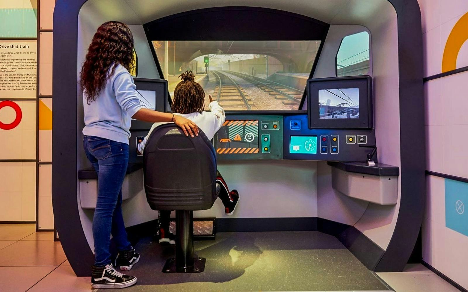 Visitors interact with a train simulator at the London Transport Museum.