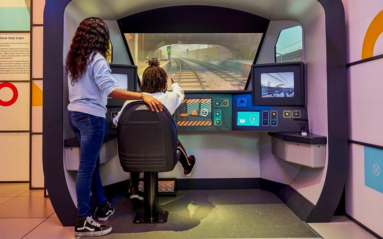 Visitors interact with a train simulator at the London Transport Museum.